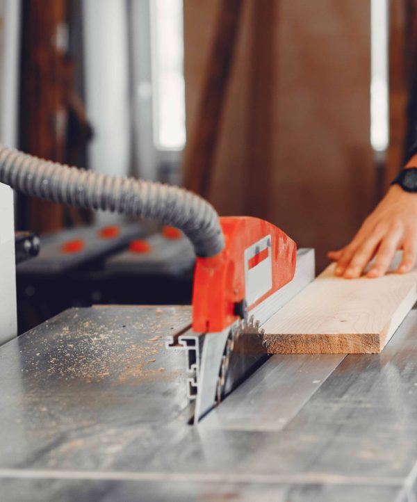 A man carves a tree. The carpenter works with saw in a studio. An engineer provides a tree shape